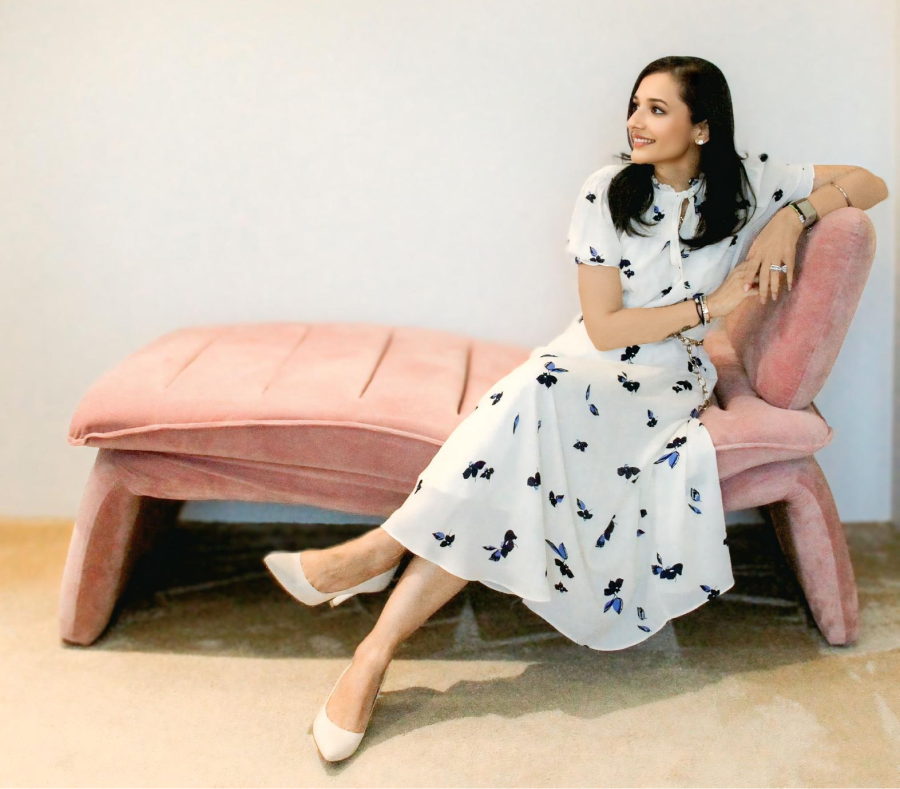 A woman sitting on a pink lounge chair, looking to the side.